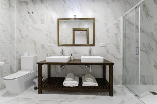 un bagno con due lavandini, uno specchio e un water di Hotel Rural Alecook a Valcabado