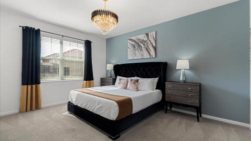a bedroom with a large bed and a chandelier at Upstay Family Home w Pool, Cinema & Games Room in Kissimmee