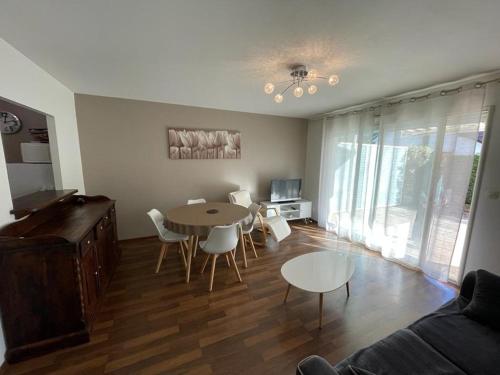 a living room with a table and chairs and a couch at Superbe appartement très spacieux en centre ville in Capbreton