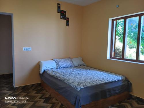un piccolo letto in una stanza con una finestra di The Kodai Fantasy a Kodaikānāl