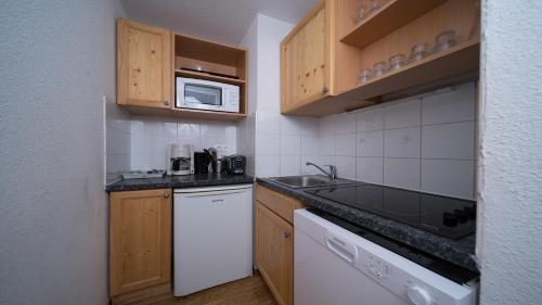 une petite cuisine avec un évier et un micro-ondes dans l'établissement Central Park N318 - 2P6C, à Allos