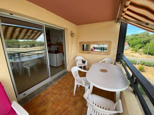 d'un balcon avec une table et des chaises blanches. dans l'établissement Appartement proche plage dans résidence avec piscine, à Capbreton