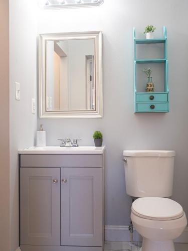 a bathroom with a toilet and a sink and a mirror at Historic Townhouse - Heart of Little Italy in Baltimore