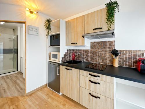 une cuisine avec des armoires en bois et un comptoir noir dans l'établissement Le Winston - Studio Cosy - Métro - Rennes, à Rennes