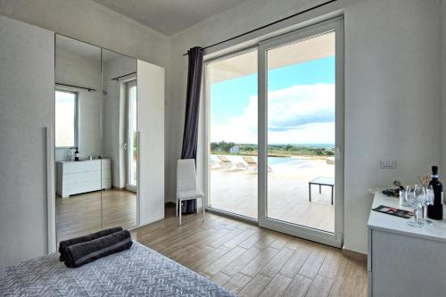a bedroom with a large sliding glass door leading to a patio at Villa Infinito by PosarelliVillas in Castelvetrano Selinunte