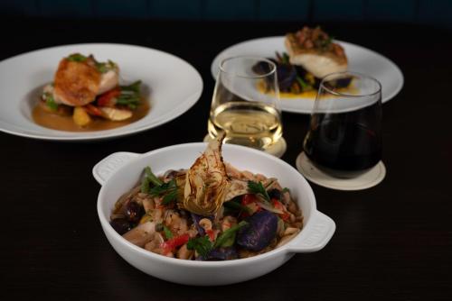 a table with plates of food and glasses of wine at Toor Hotel Toronto, Part Of Jdv By Hyatt in Toronto