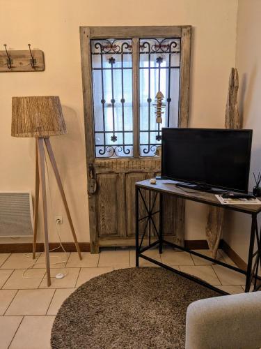 une chambre avec une table, une télévision et une porte dans l'établissement Les Jumelles de la Baie, à Villers-sur-Authie