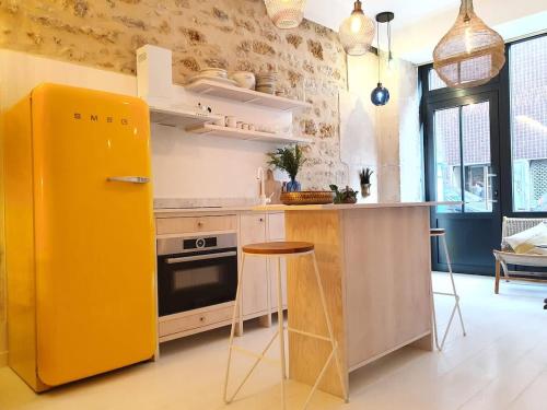 Il comprend une cuisine équipée d'un réfrigérateur jaune et d'un comptoir. dans l'établissement Bel appartement - Jardin des plantes, à Paris