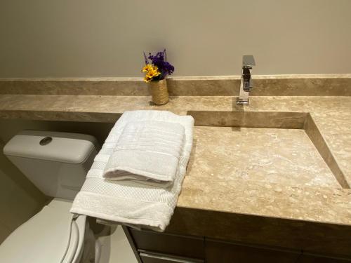 a bathroom with a sink with towels on a counter at Apartamento em frente ao novo shopping in Ribeirão Preto