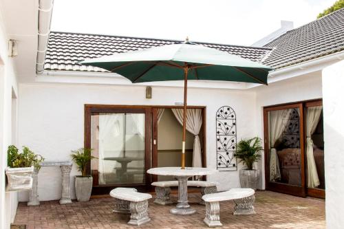 a patio with a table and two benches and an umbrella at Victoria Heights B&B in George