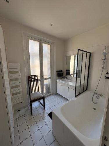 La salle de bains est pourvue d'une baignoire, d'une chaise et d'un lavabo. dans l'établissement Appartement 140m2 proche des Champs Elysées, à Paris