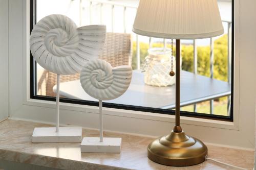 two shell sculptures on a table next to a lamp at Strandkojen in Trassenheide
