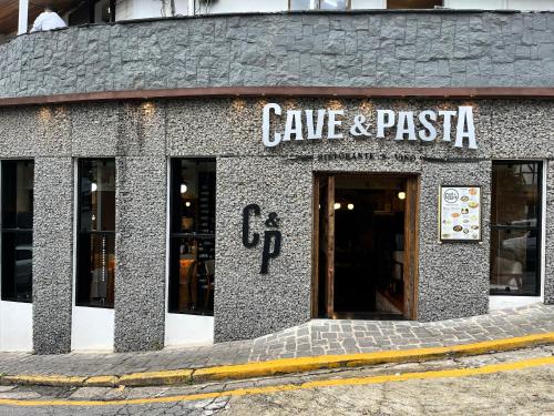 a stone building with a cave and pizza sign on it at Center Suiço Flats in Campos do Jordão