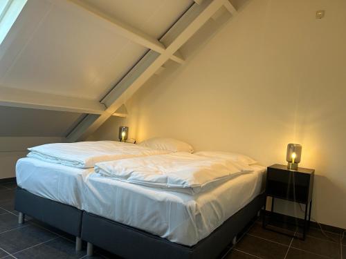 a bedroom with a large bed with white sheets at Wijndomein Joris in Slenaken