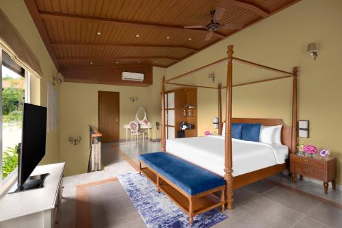 a bedroom with a canopy bed with a blue bench at Gateway Coorg in Madikeri