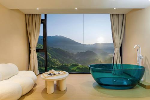 a bathroom with a large glass tub in front of a window at Longji Rice Terraces Homestead Resort in Longsheng