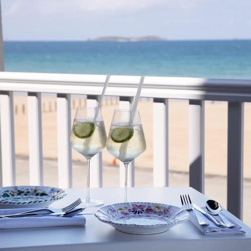 two glasses of wine and plates on a table at Hôtel Alba Saint-Malo Plage du Sillon in Saint Malo