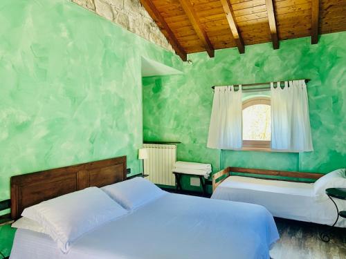 カスティリオーネ・ディンテルヴィにあるAgriturismo Il Talento Nella Quieteの緑豊かなベッドルーム(ベッド2台、窓付)