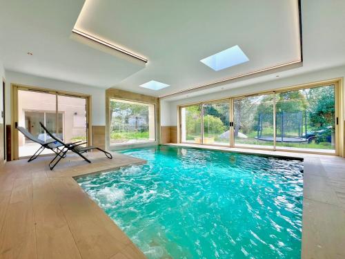 - une piscine intérieure d'eau bleue dans une chambre avec fenêtres dans l'établissement L’Étoile de Dan, Piscine, Spa & Jeux, à Crespian