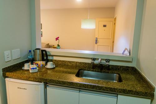 a kitchen counter with a sink and a mirror at Travel Inn Flats Jardins in Sao Paulo