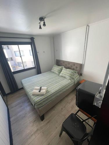a small bedroom with a bed and a television at VOY Hostales - 4 Norte in Viña del Mar