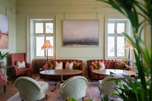 a living room with couches and tables and windows at The Falmouth Hotel in Falmouth