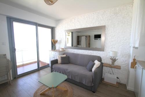 un salon avec un canapé et un miroir dans l'établissement magnifique studio vue mer, à Canet