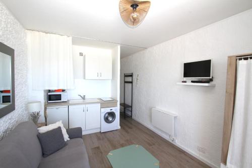 un salon avec un canapé et une télévision au mur dans l'établissement magnifique studio vue mer, à Canet