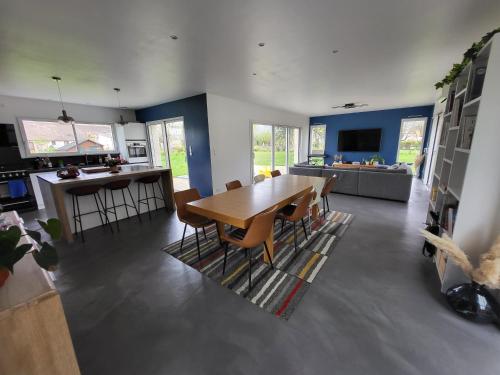 Il dispose d'une cuisine et d'un salon avec une table et des chaises en bois. dans l'établissement Maison moderne 180 m2, à 10 min du Circuit des 24h du Mans, à Fatines