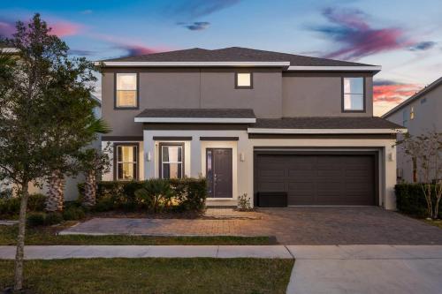 a house with a garage at dusk at Upstay Vibrant Home w Themed Rooms Pool & Games in Kissimmee