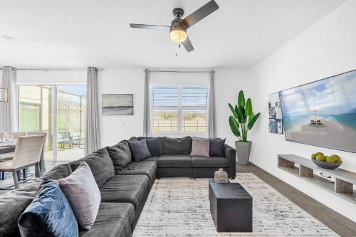 a living room with a couch and a ceiling fan at Upstay Vibrant Home w Themed Rooms Pool & Games in Kissimmee