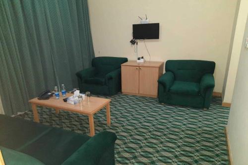 a living room with two green chairs and a table at OYO 142 Al Sharqiya Sands Hotel in Ibrā