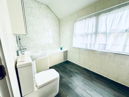 a bathroom with a toilet and a sink and a window at Stylish 1 Bedroom Flat in the Heart of Staines in Staines upon Thames