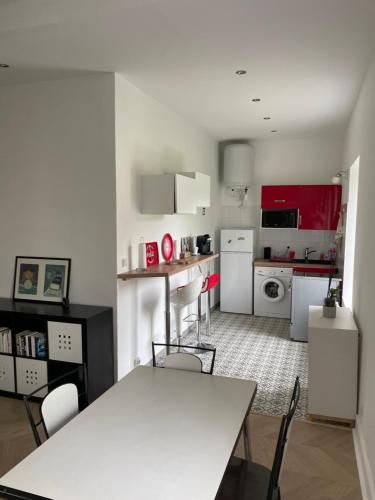 une cuisine avec des placards rouges, une table blanche et des chaises dans l'établissement Appartement collonges bord de Saône, à Collonges-au-Mont-dʼOr