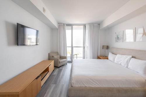 ハランデール・ビーチにある2B 2B Beachfront Pool Gym, and Restaurantのベッドと壁掛けテレビのある寝室