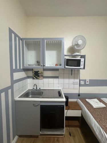 a small kitchen with a sink and a microwave at Anwar House in London