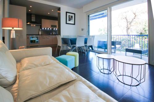 Il comprend un salon avec un canapé et des tables ainsi qu'une cuisine. dans l'établissement CHENES Lumineux Vue Mer Clim Confort Terrasses Parking, à Antibes