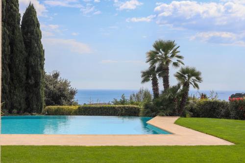 une piscine dans une cour avec des palmiers dans l'établissement Magnifique Villa Provençal avec Piscine et Vue Mer, à Antibes