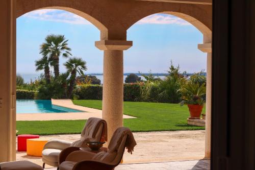 Elle offre une vue sur une terrasse avec 2 chaises et une piscine. dans l'établissement Magnifique Villa Provençal avec Piscine et Vue Mer, à Antibes