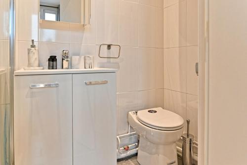 une salle de bain blanche avec des toilettes et un lavabo dans l'établissement Studio élégant à Neuilly entre Paris et La Défense, à Neuilly-sur-Seine