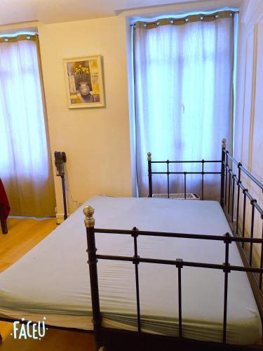 - un lit dans une chambre avec 2 fenêtres dans l'établissement Leaf's home, à Paris