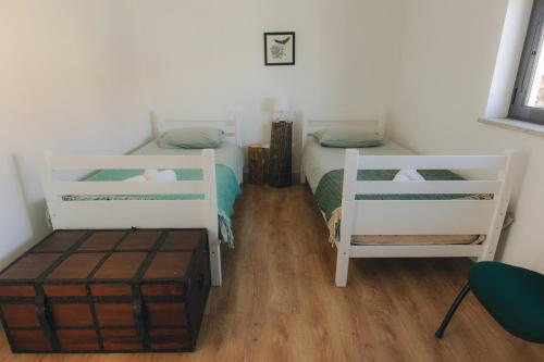 a bedroom with two twin beds and a wooden floor at Centro Rewilding in Vale de Madeira