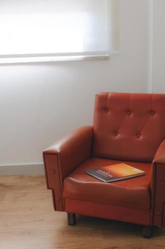 a red leather couch with a book on it at Centro Rewilding in Vale de Madeira