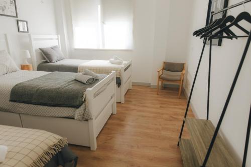 a small bedroom with two beds and a chair at Centro Rewilding in Vale de Madeira
