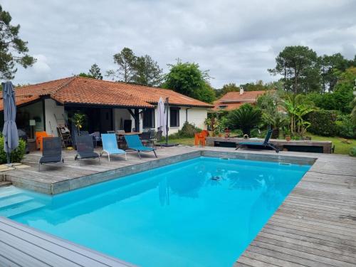 une piscine avec des chaises bleues et une maison dans l'établissement house with heated pool and jacuzzi, à Soorts-Hossegor