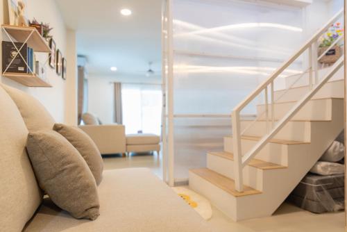 a living room with a couch and a staircase at Sunny's Cozy Home in Bophut 