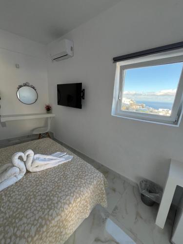 a white bedroom with a bed and a window at Stella Nomikou Apartments in Firostefani