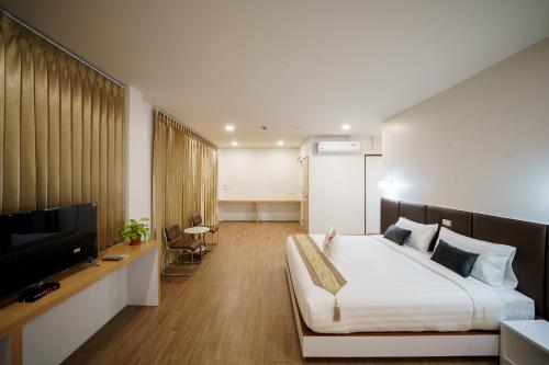a bedroom with a bed and a flat screen tv at Silom Residence Khlonghae Hotel in Hat Yai