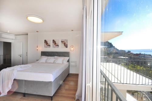 a white bedroom with a bed and a balcony at Villa Iva in Omiš