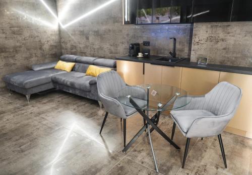 a living room with a couch and a glass table and chairs at Luna Apartments B in Suceava